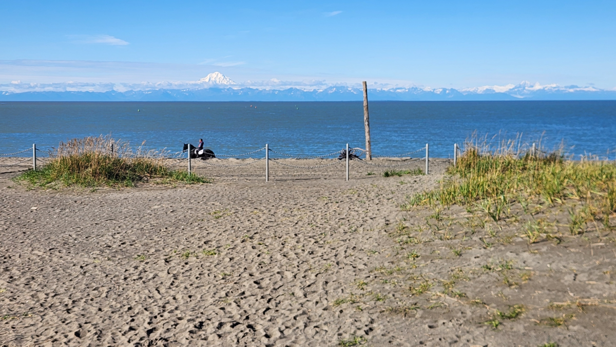 Kasilof River Special Use Area – Horseback Riding with Mountain Views - Dohrn Travels Horseback rider on the beach at Kasilof River Special Use Area, Alaska, with ocean and snow-capped mountain views.