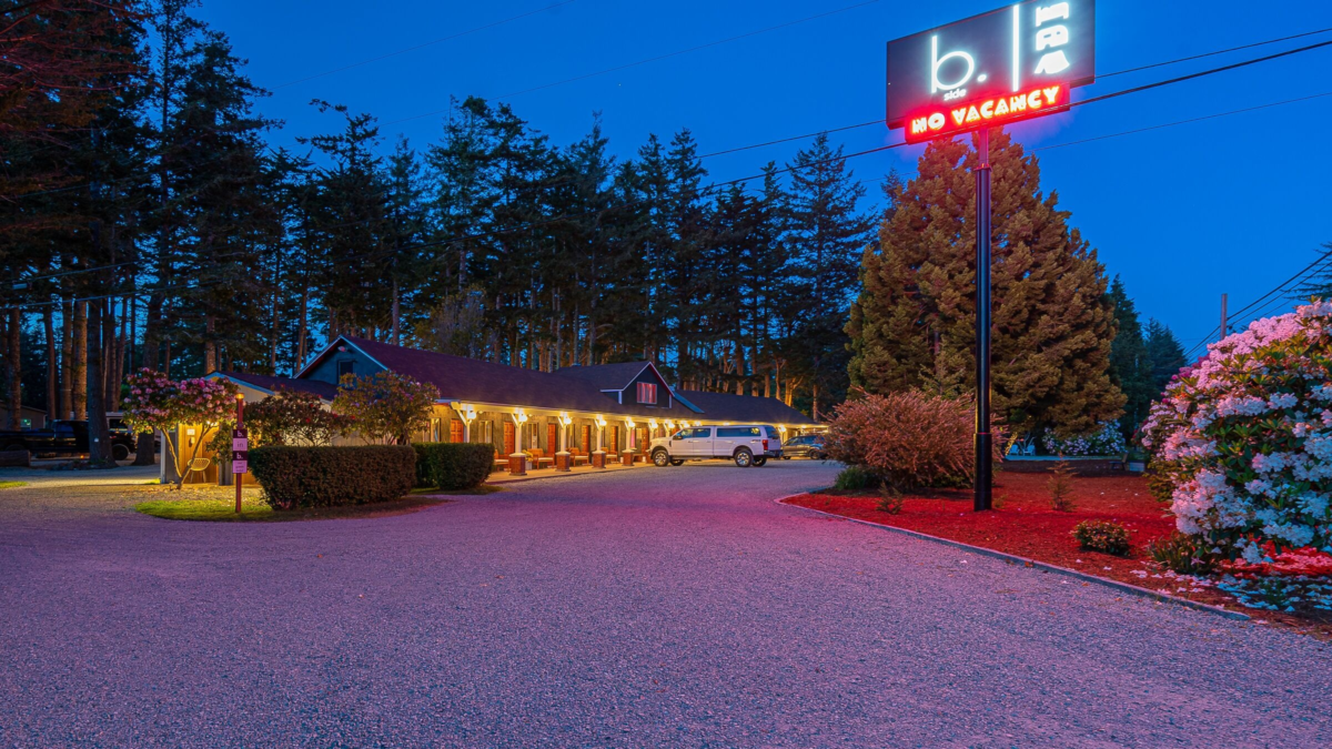 b.side motel + rv in Bandon Oregon illuminated at night with cozy retro-style lodging surrounded by trees